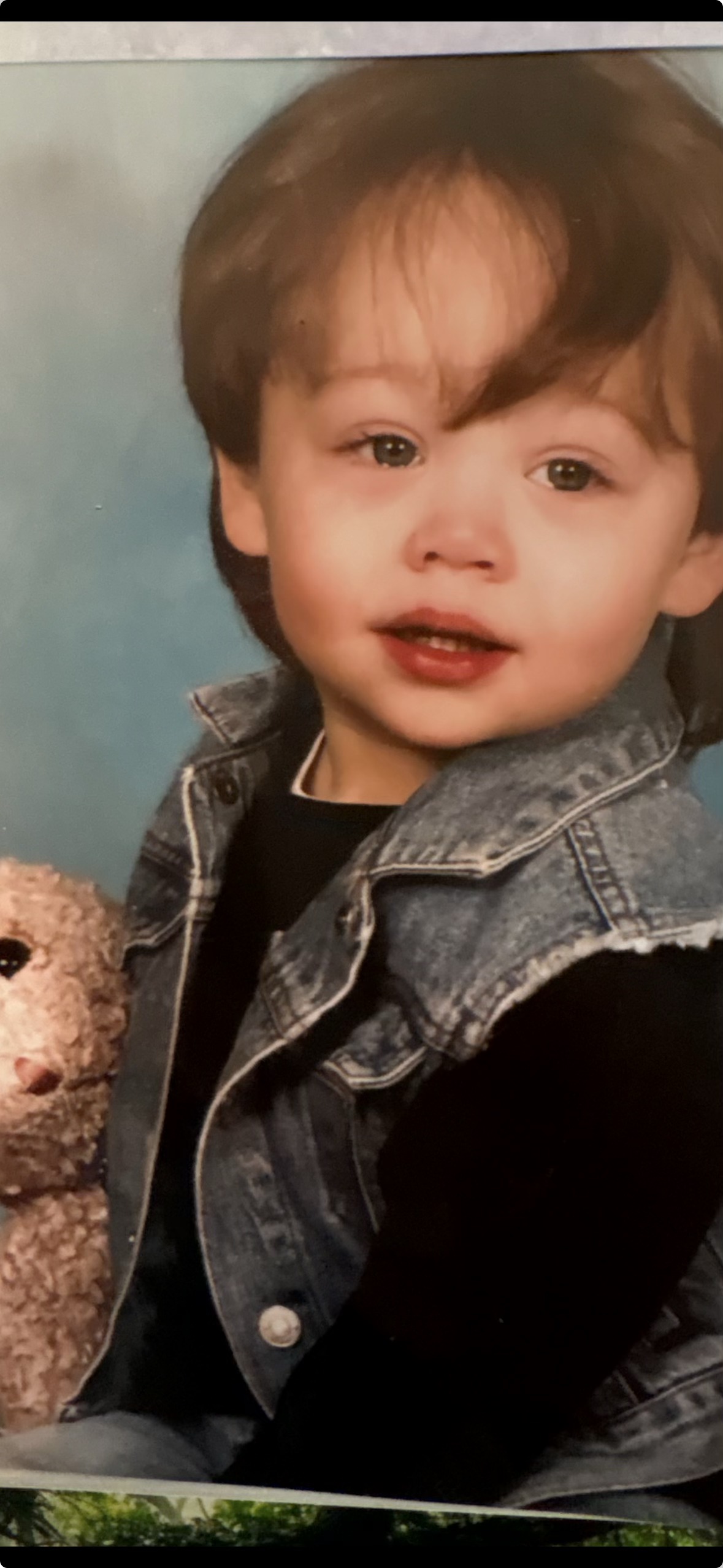 Brandon as a young child, holding a teddy bear